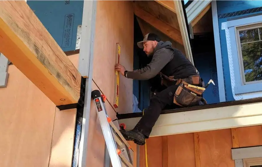 Construction worker using level on building project