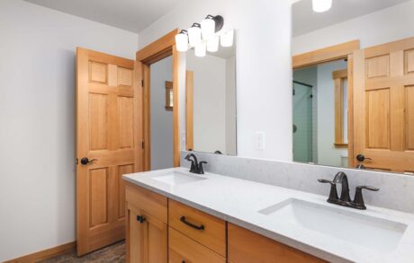 Custom Home Walden_Loop – Bathroom Modern bathroom interior with wooden cabinets and mirrors