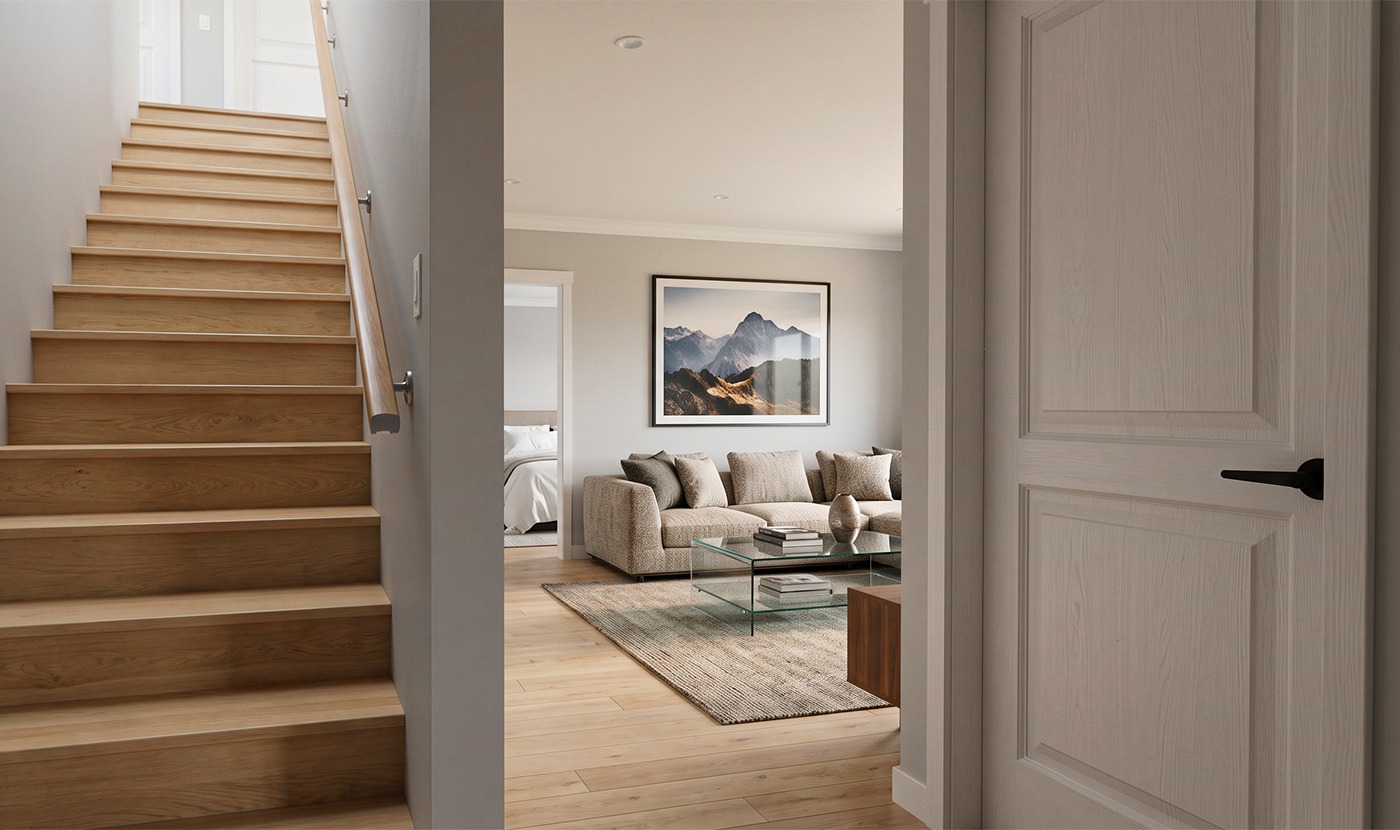 View from an entry hall into a living room with a beige sofa, glass coffee table, and framed mountain art on the wall