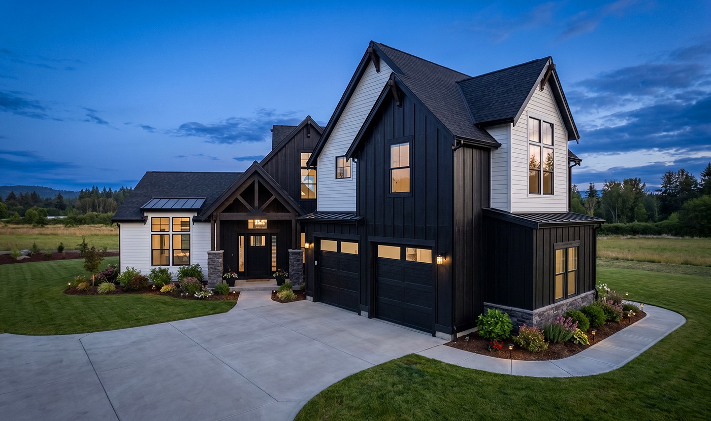 Modern two-tone house exterior at dusk with black and white siding and warmly lit windows.