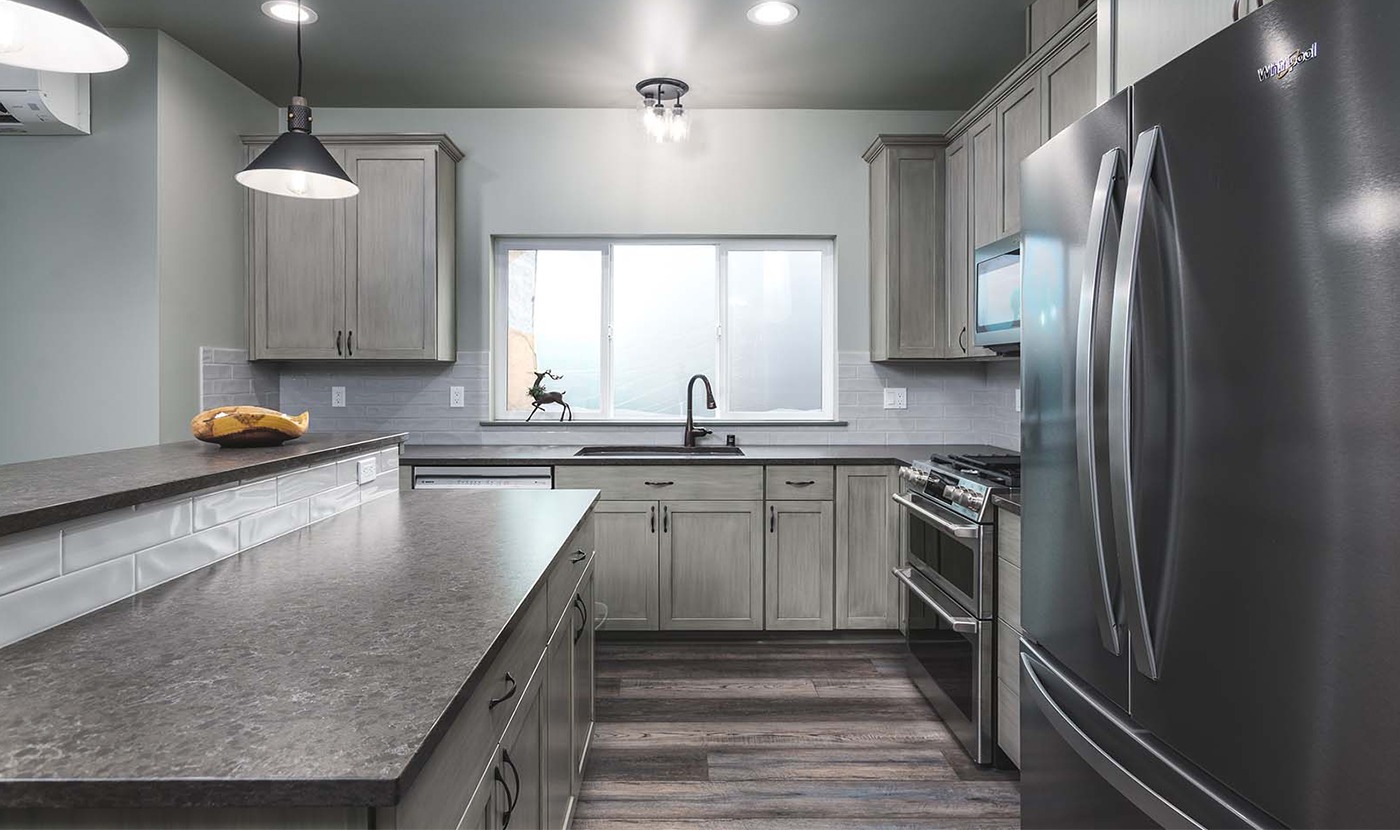 Modern U-shaped kitchen with gray cabinetry, stainless appliances, and a large window above the sink.
