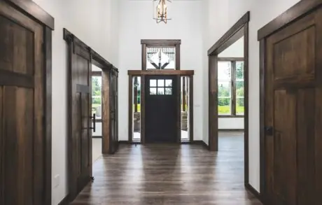 Redwood Custom Entry - Inspire Homes Rustic wooden doors in a modern hallway.