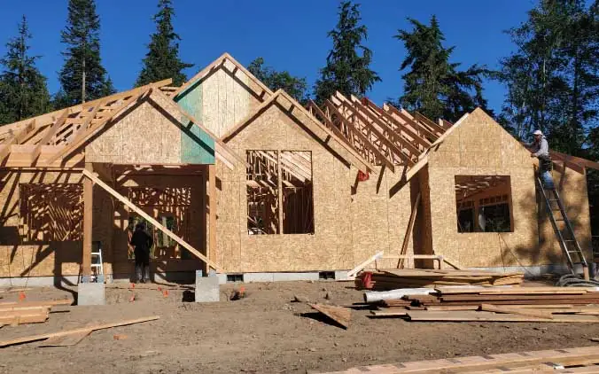 Wooden house under construction in forest setting